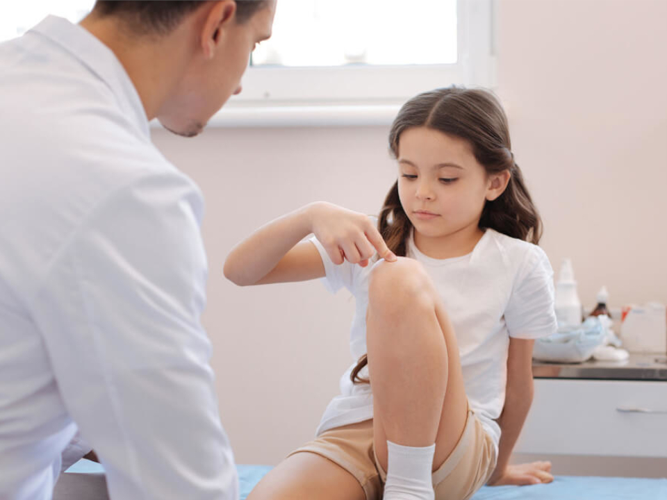 Lekarz badający kolano dziecka